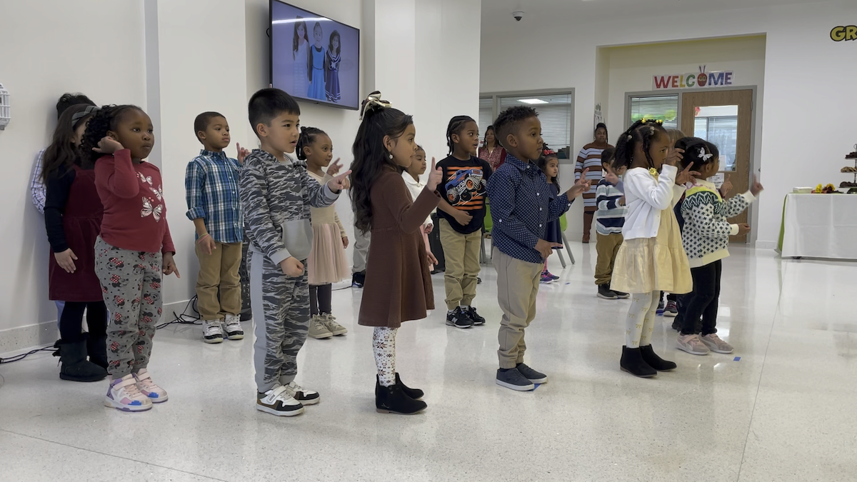 A group of early learners performs a song for ceremony guests
